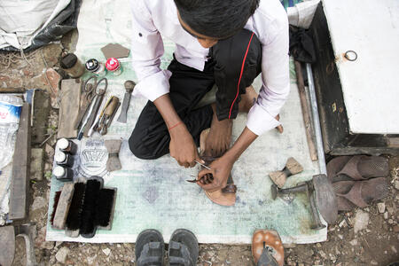 This young shoe repairer is quite mobile. He moves his entire enterprise wherever the business is. 