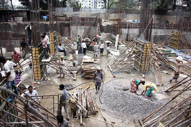 Women in Bangladesh building foundation on construction site.